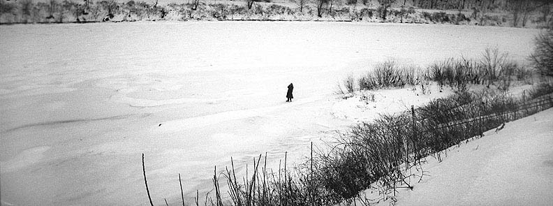 man standing far away on frozen river